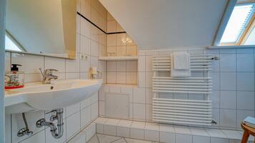 A modern bathroom with a large sink, a mirror, a towel rack, and a skylight.