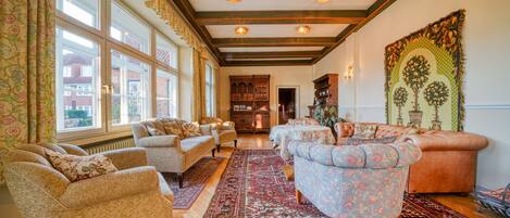 A spacious living room with multiple seating areas, large windows, and a traditional fireplace.