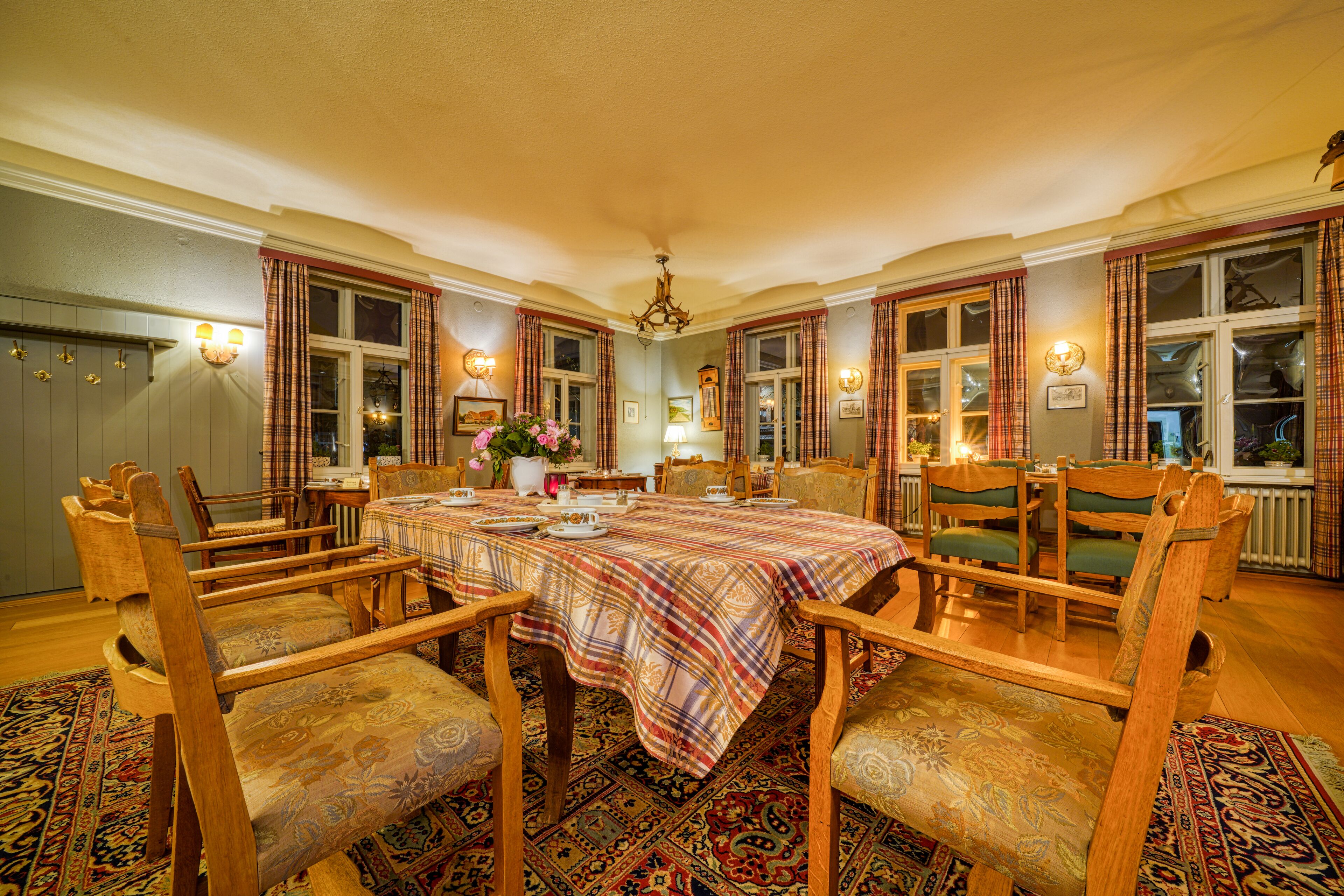 A dining room with a large table, chairs, and a chandelier.