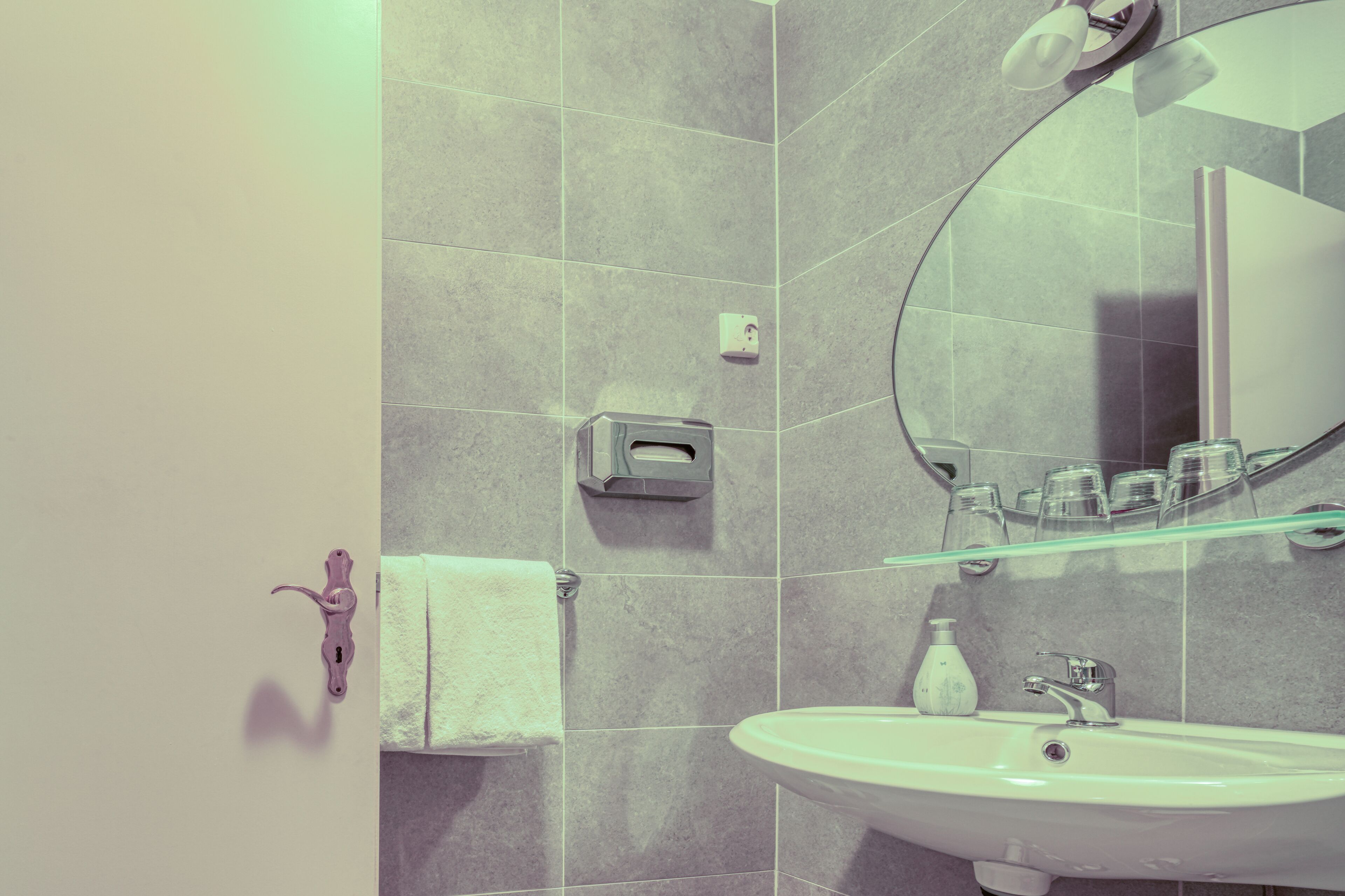 A bathroom with a white sink, a mirror, and a towel rack.