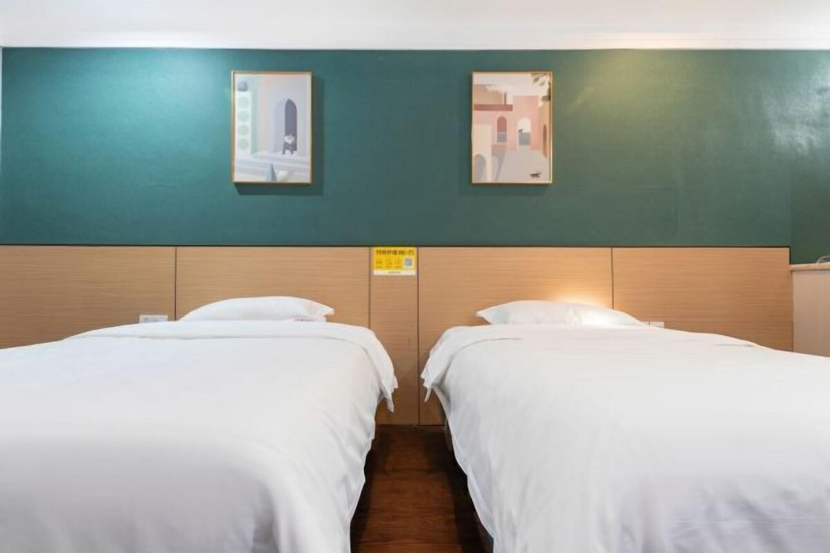 Et hotelværelse med to enkeltsenge, vægge i teal farve og billeder hængende over sengene.