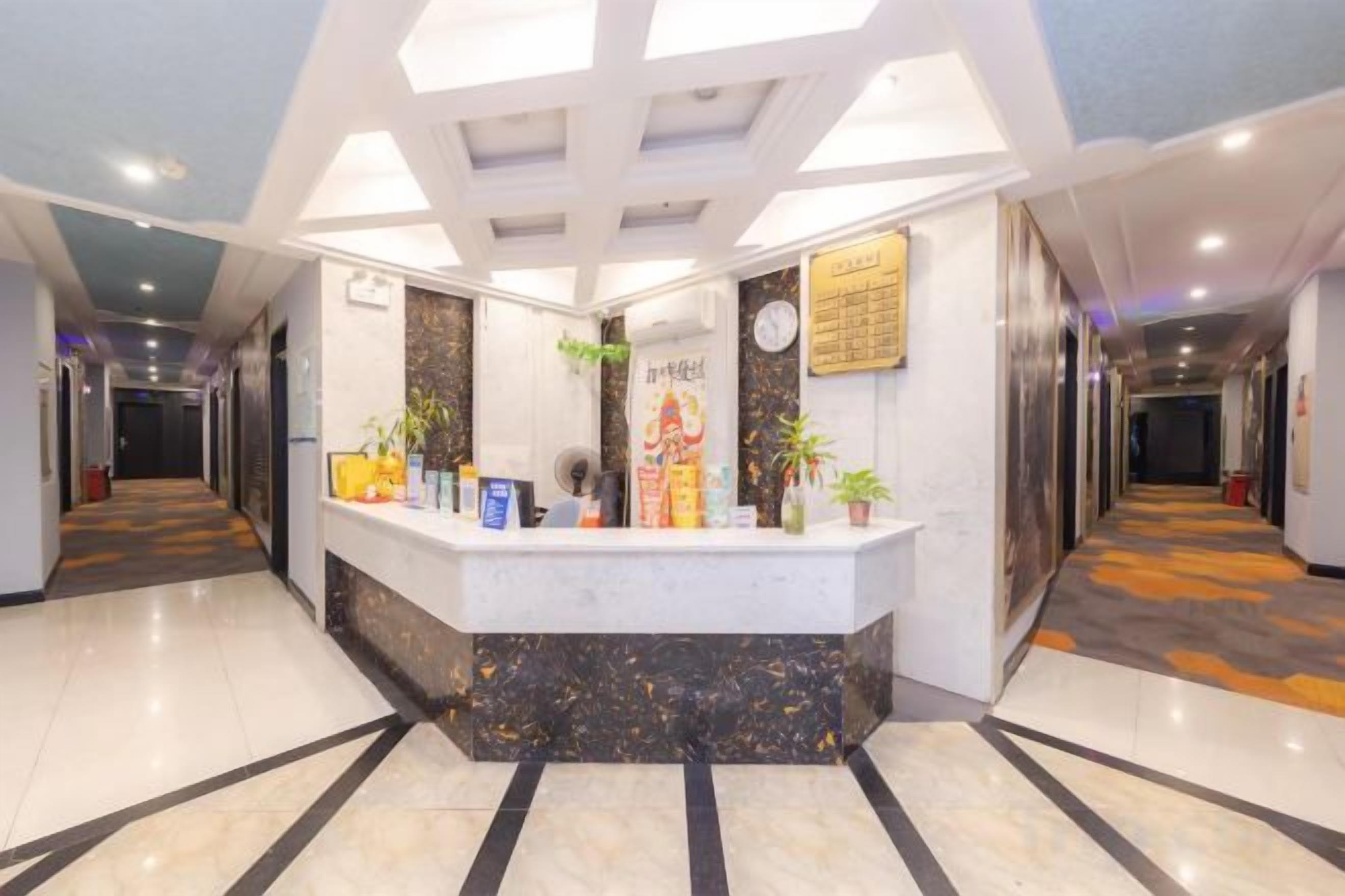 Área de recepção de hotel com balcão, relógio e placa na parede.