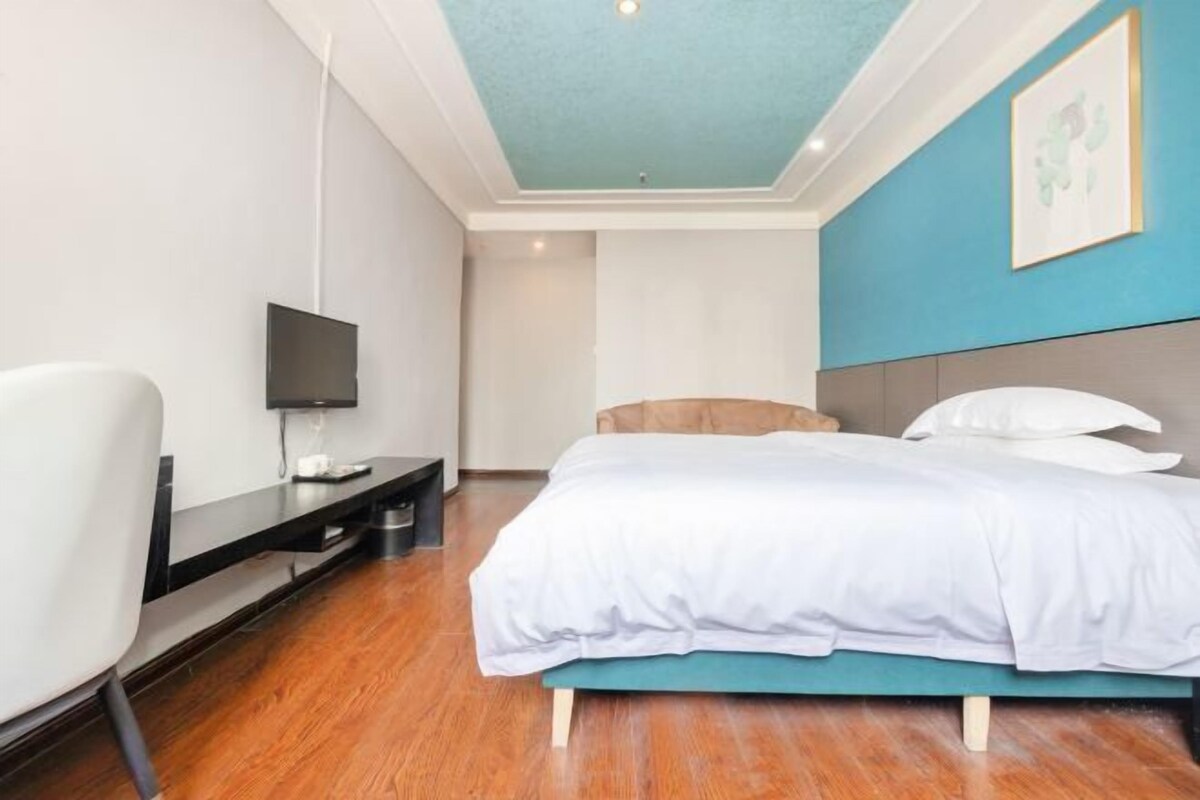 Et moderne hotelværelse med seng, fjernsyn, skrivebord og stol.