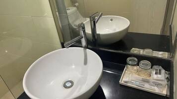 Un baño con un lavamanos blanco, un espejo y una bandeja con dos frascos de vidrio.
