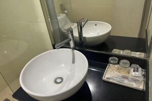 A bathroom with a white sink, a mirror, and a tray with two glass jars.
