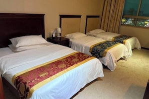 A hotel room with two beds, a nightstand, a lamp, and a window with curtains.