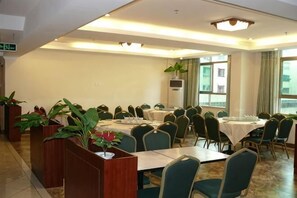 A conference room with multiple tables and chairs, large windows, and potted plants.
