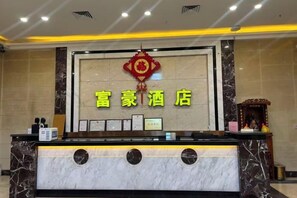 A hotel reception desk with a marble counter, a red decorative hanging, and a framed sign with Chinese characters. - VIP Hotel (Kaiping)