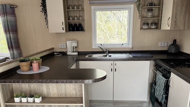 A compact kitchen with a built-in sink, stove, and storage cabinets. - Vacation chalet on a campsite (Windeck)