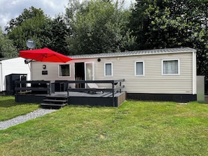 Une maison mobile dotée d’un patio, d’un parasol rouge et d’une antenne parabolique.