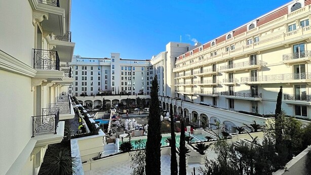 A hotel courtyard with multiple balconies, a swimming pool, and a central open area. - Viva Riviera Carlton Riviera Luxury Collection (Cannes)