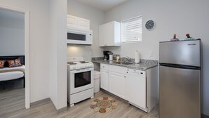 A compact kitchen with white cabinets, a stainless steel refrigerator, a microwave, a stove, and a dishwasher. - TWO Condos! Side by Side Curated Suites! Sleeps 18! Parking! (Nashville)