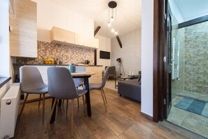 A modern kitchen with a dining area, wooden cabinets, and a stone wall.