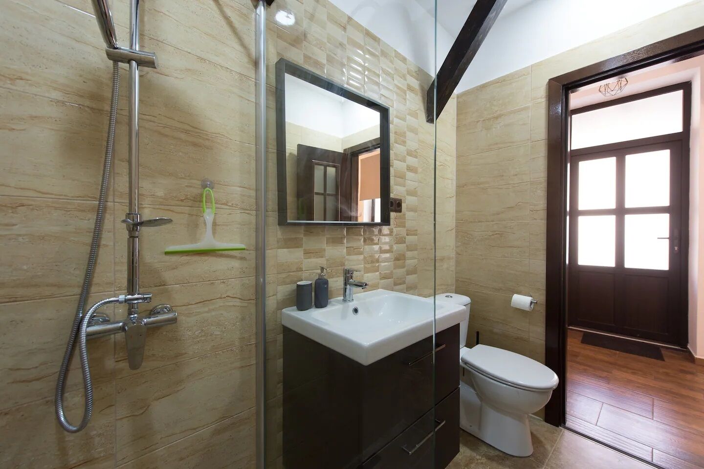 A bathroom with a glass shower enclosure, a white sink, a toilet, and a mirror above the sink.