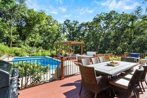 Eine Terrasse mit Pool, Gartenmöbeln und einer Pergola.