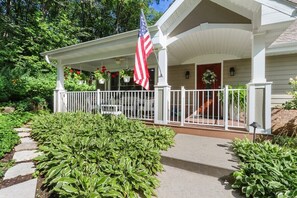 Ein Haus mit überdachter Veranda, einem weißen Zaun und einer amerikanischen Flagge.