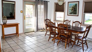 Un comedor con una mesa y sillas de madera, un espejo y una ventana con persianas.