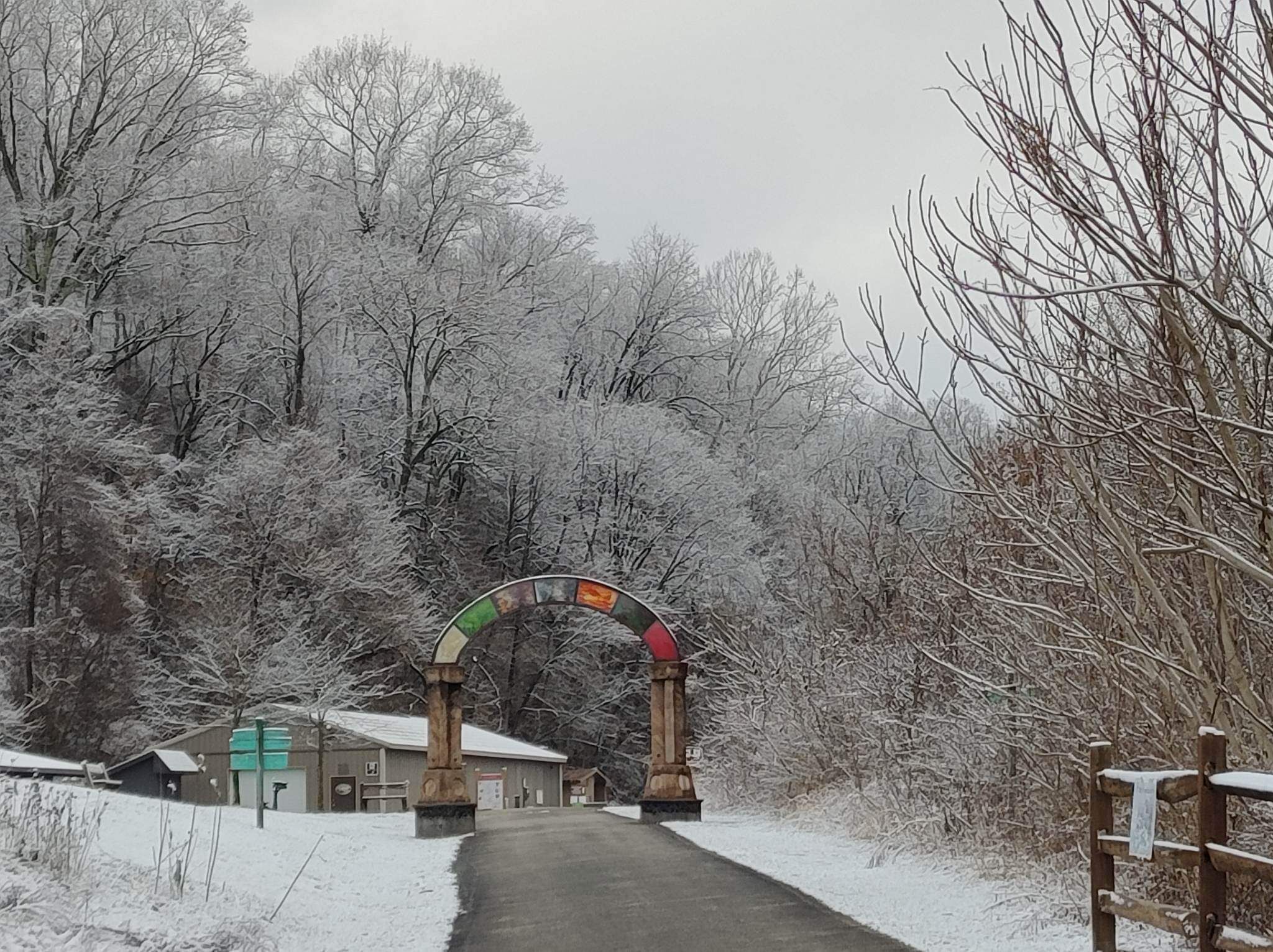 Un sentiero innevato che conduce a un edificio con un arco in legno.
