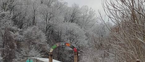 A snow-covered pathway leading to a building with a wooden archway.