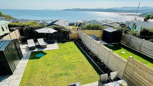 Patio trasero con piscina, mobiliario exterior y vista al mar.