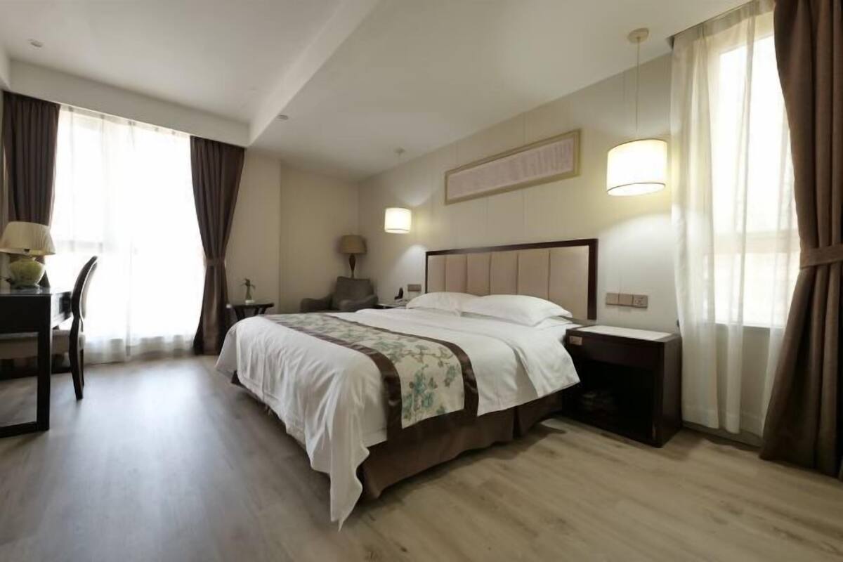 Une chambre d’hôtel avec un grand lit, un bureau avec une chaise, une lampe et une table de chevet.