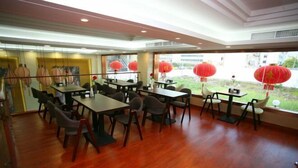 A dining area with tables and chairs, large windows, and red lanterns. - Baihe Boutique Hotel (Yueqing Beibaixiang Store) (Yueqing)