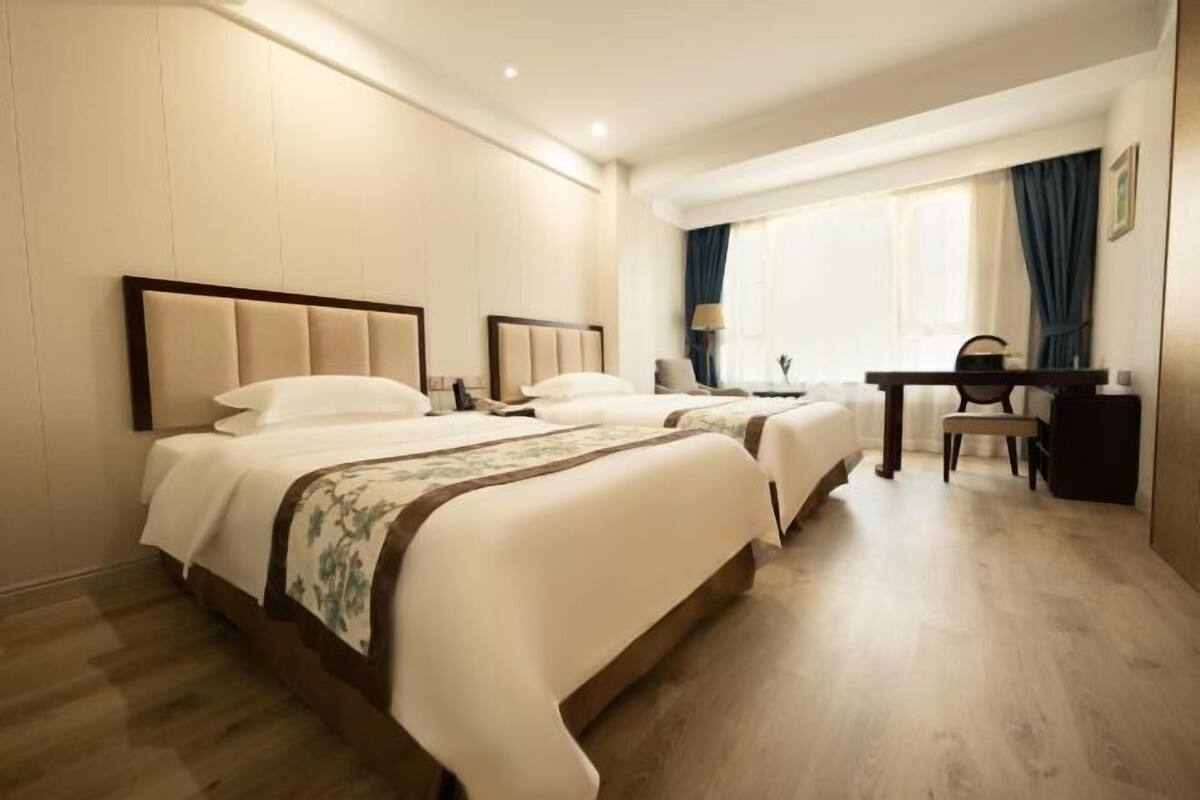 Une chambre d’hôtel avec deux lits, un bureau et une chaise.