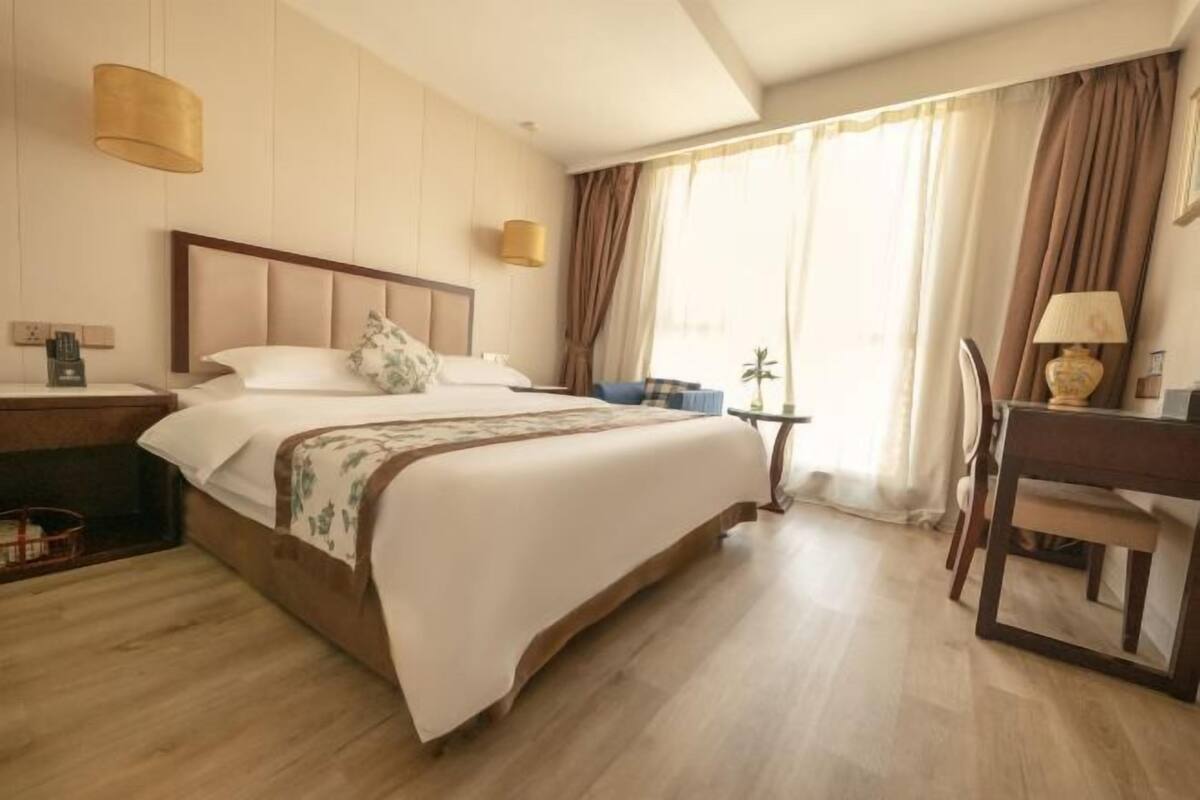 Une chambre d’hôtel avec un grand lit, un bureau, une chaise et une petite table.