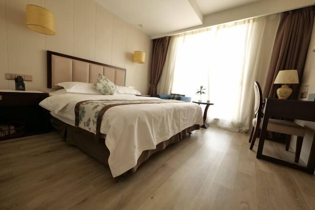 Une chambre d’hôtel avec un grand lit, un bureau, une chaise et une petite table.