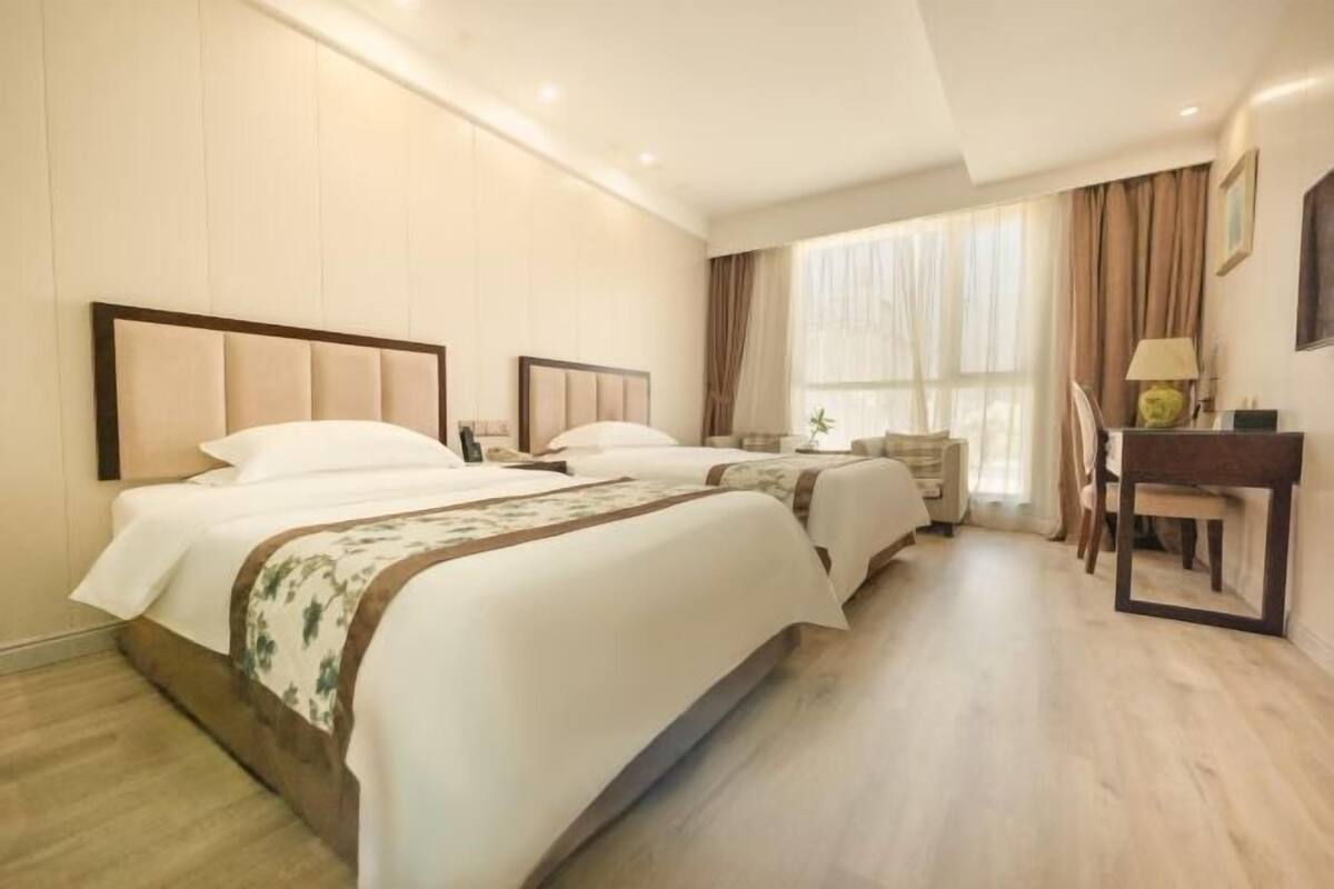 Une chambre d’hôtel avec deux lits, un bureau et une chaise.