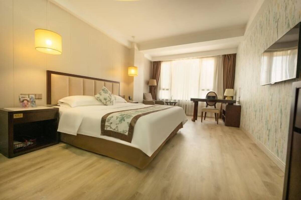 Une chambre d’hôtel avec un grand lit, des tables de chevet, un bureau et un téléviseur.