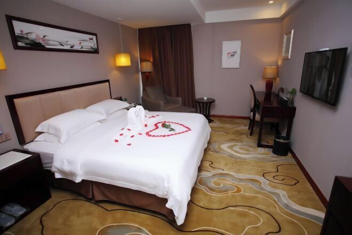 Ein Hotelzimmer mit einem Bett, einem Schreibtisch, einem Stuhl und einem kleinen Tisch.