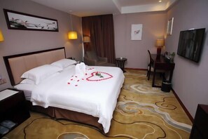 Ein Hotelzimmer mit einem Bett, einem Schreibtisch, einem Stuhl und einem kleinen Tisch.