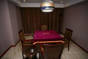 Une chambre d’hôtel équipée d’une table à manger, de quatre chaises, d’une petite table d’appoint, d’un lampadaire et d’un grand lustre au plafond.