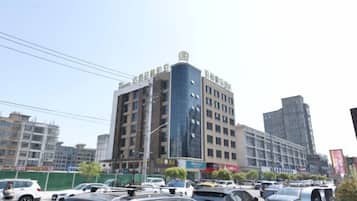 A multi-story building with commercial signage on the ground floor, surrounded by parked cars and other buildings.