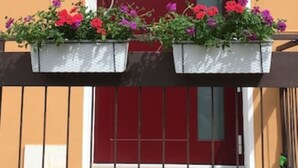 Un bâtiment avec une porte rouge et un balcon orné de jardinières.