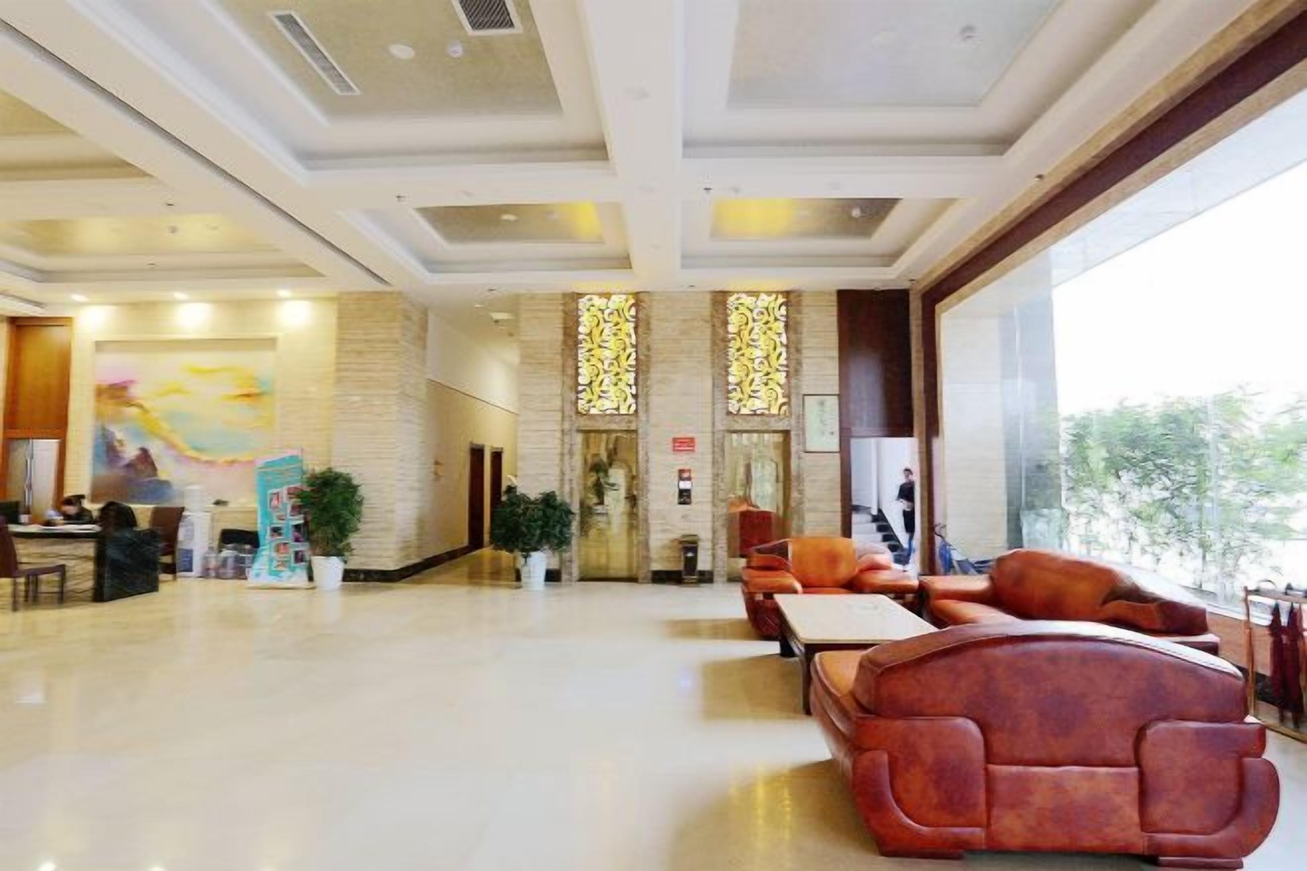 A hotel lobby with a reception desk, seating area, and large windows.