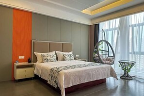 Een moderne hotelkamer met een groot bed, een nachtkastje, een hangstoel en uitzicht op de stad.