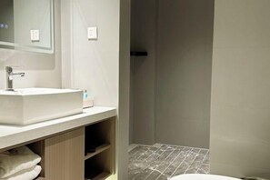 Een badkamer met een wit wastafelmeubel, spiegel en betegelde vloer.