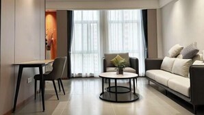 A modern living room with a sofa, a round coffee table, a dining table, and a chair.