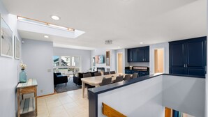 A modern kitchen with dark cabinets, a dining area with a large table, and a visible island with a countertop.