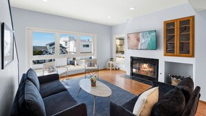 A modern living room with a fireplace, large windows, and a cozy seating area.