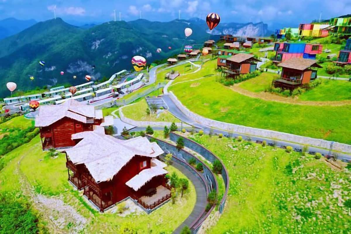 A scenic village with traditional houses, a winding road, and a mountain backdrop.