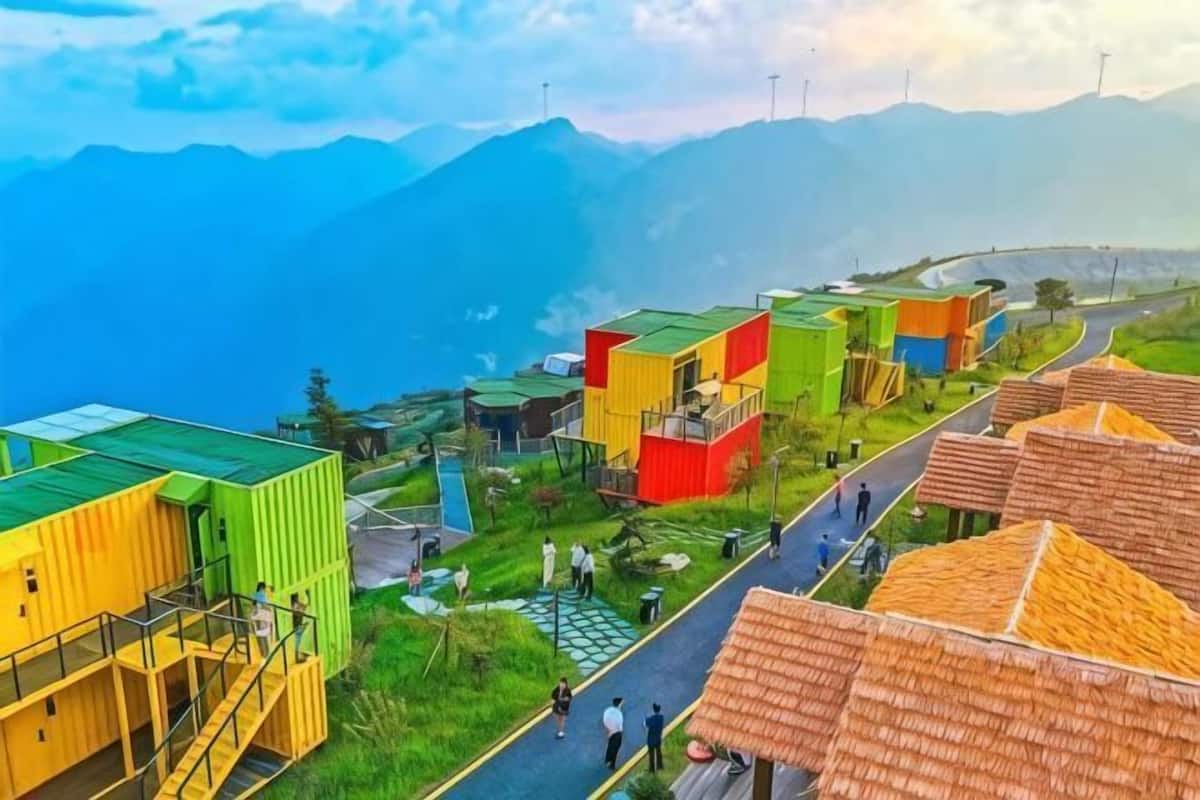 A village with colorful buildings, a road, and mountains in the background.