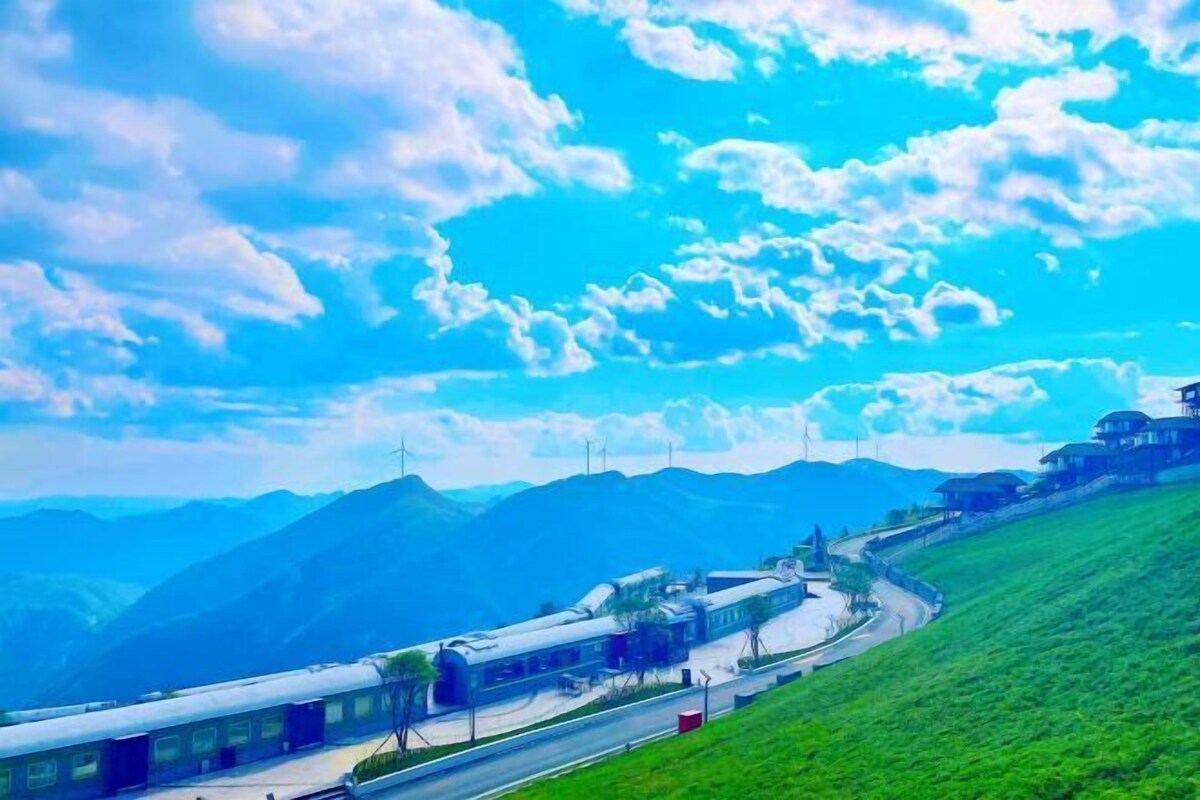 Ein Zug auf Gleisen vor einer Berglandschaft und wolkenlosem Himmel.
