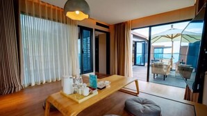 Una habitación de hotel moderna con un escritorio de madera, una zona de estar cómoda y un balcón con vistas al mar.