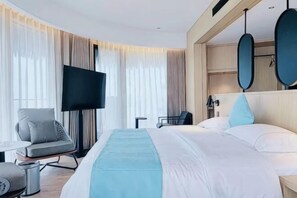 Ein Hotelzimmer mit Bett, Fernseher, Schreibtisch und Stuhl.