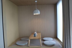 Ein modernes Zimmer mit einer Wand aus Holzlatten, einem zentralen Tisch mit einem kleinen Heizgerät und gepolsterten Sitzgelegenheiten.