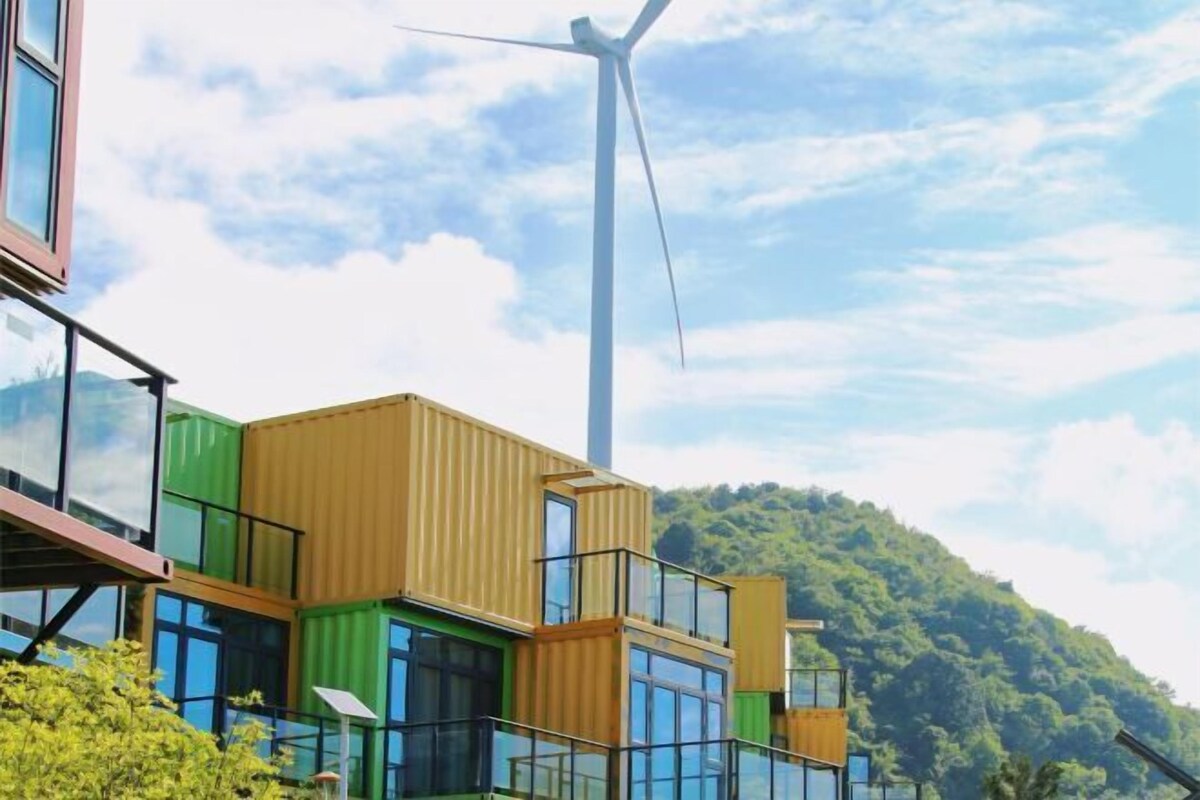 Ein modernes Gebäude mit Windkraftanlage im Hintergrund.