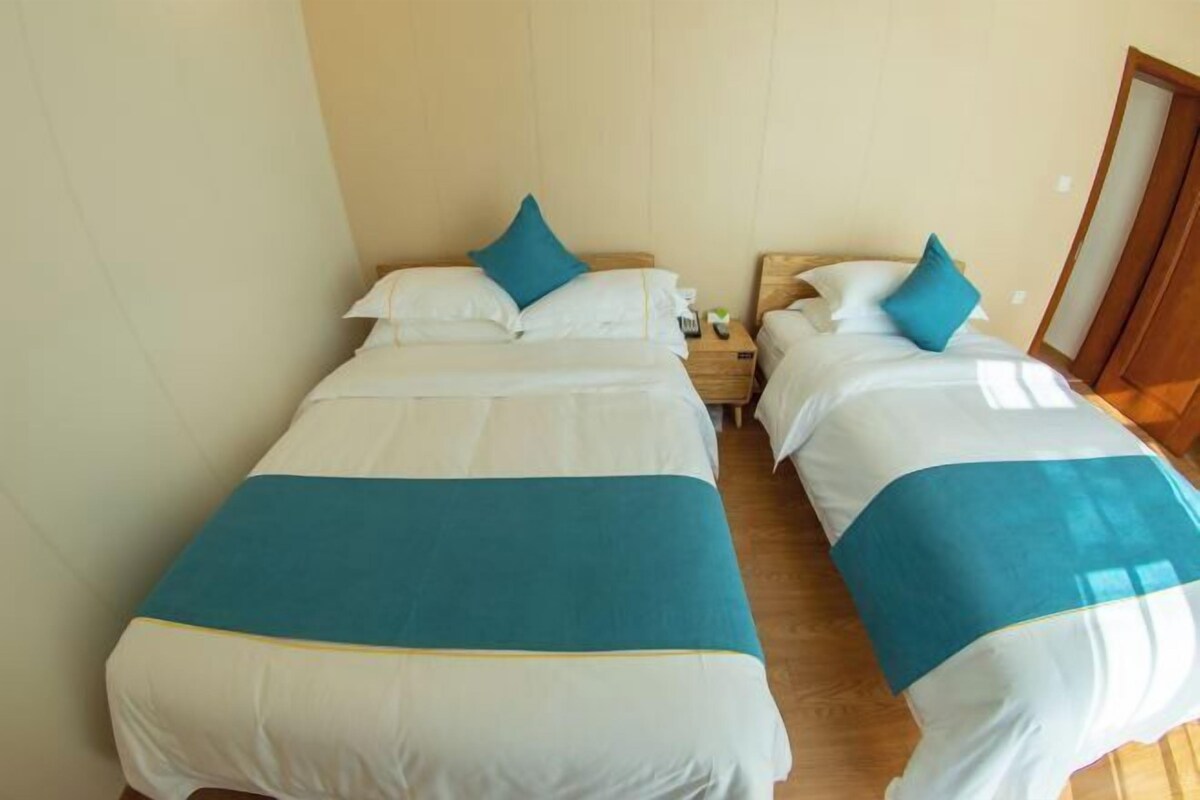 Ein Hotelzimmer mit zwei Betten, jeweils mit einer blau-weißen Tagesdecke und passenden Kissen.